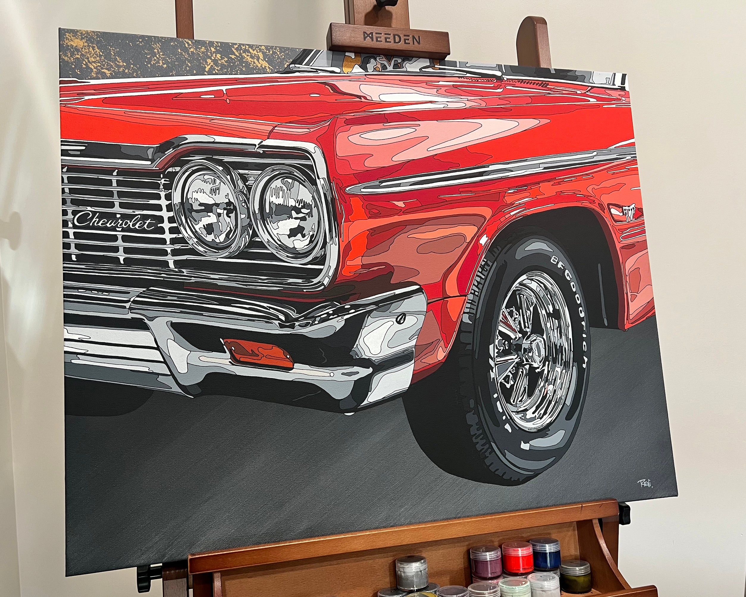 Close-up of a red Chevrolet car on an easel with art supplies below.