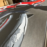 Close-up of a car's rear wing with a flame design, blurred background