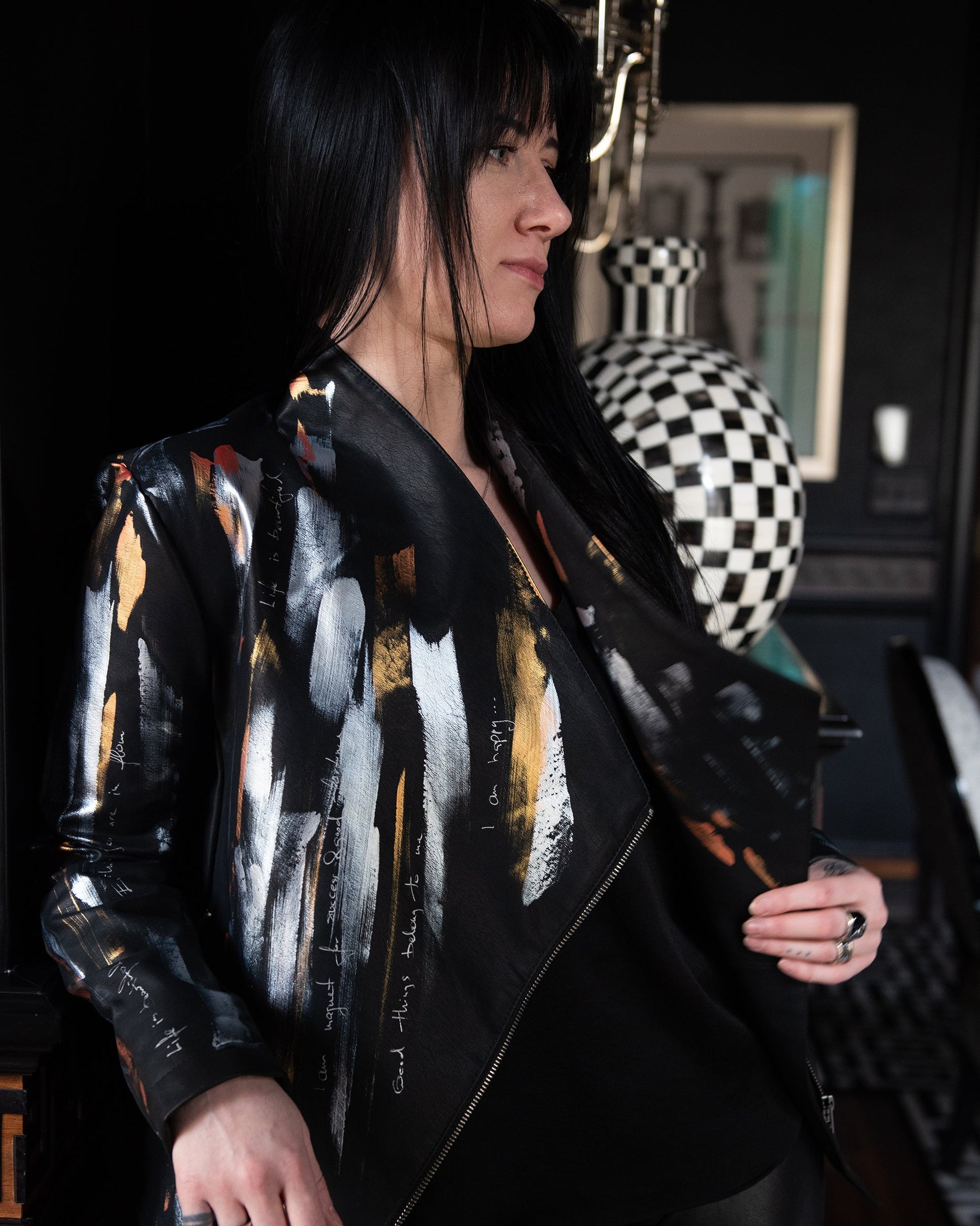 Person wearing a stylish black jacket with abstract patterns in a room with decorative elements.