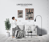 Living room with a person looking at two wall art pieces featuring wine bottles and sizes.